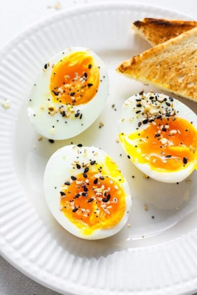 three soft boiled eggs on a plate with corners of toast