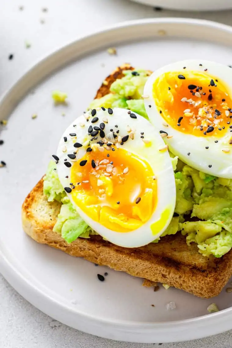 close up on avocado toast with soft boiled eggs and sesame seeds