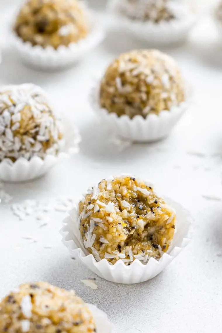 close up on an energy bite with poppy seed and coconut in a white liner