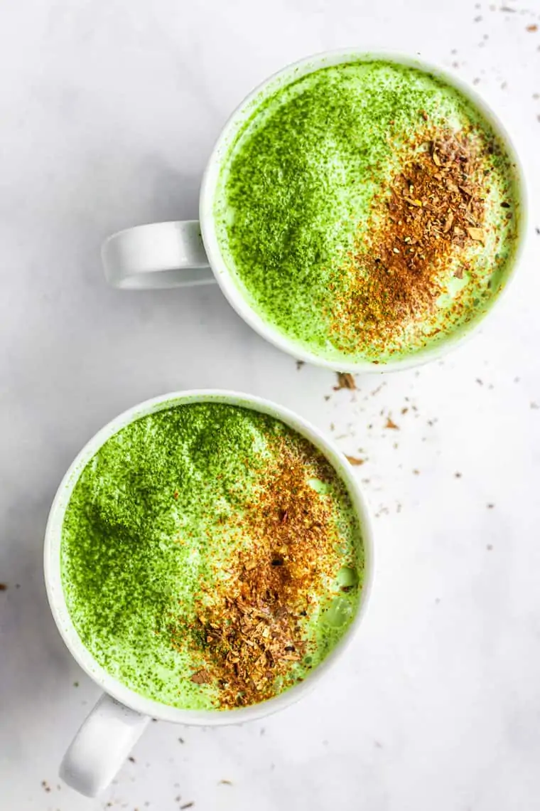 two white mugs of matcha latte with umpkin spice on top