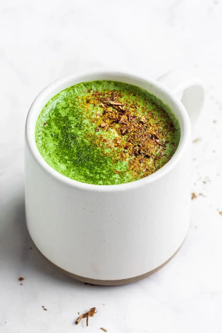 close up on a white mug of pumpkin spice matcha with pumpkin spice on top