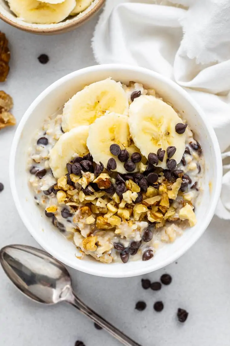 white bowl of overnight oats with chocolate chips and banana slices