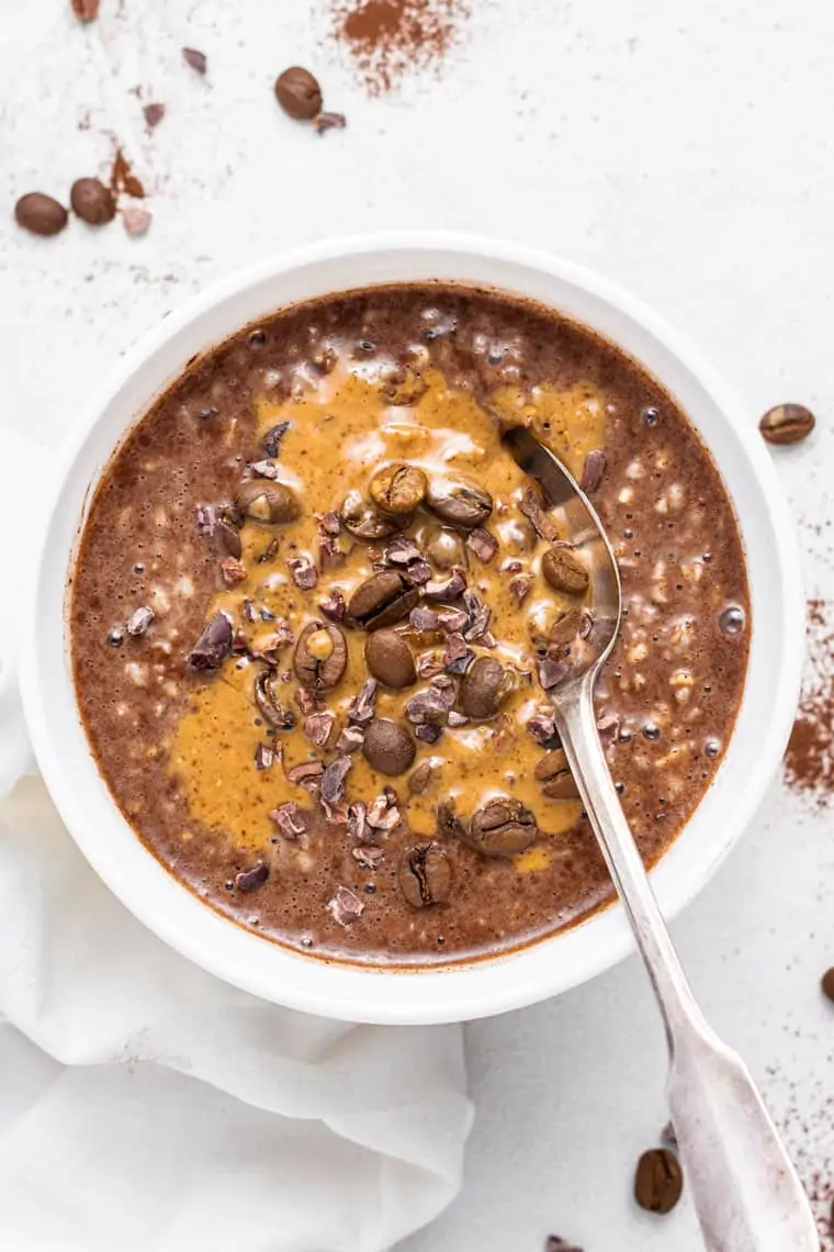 white bowl of chocolate and coffee oatmeal with coffee beans on top