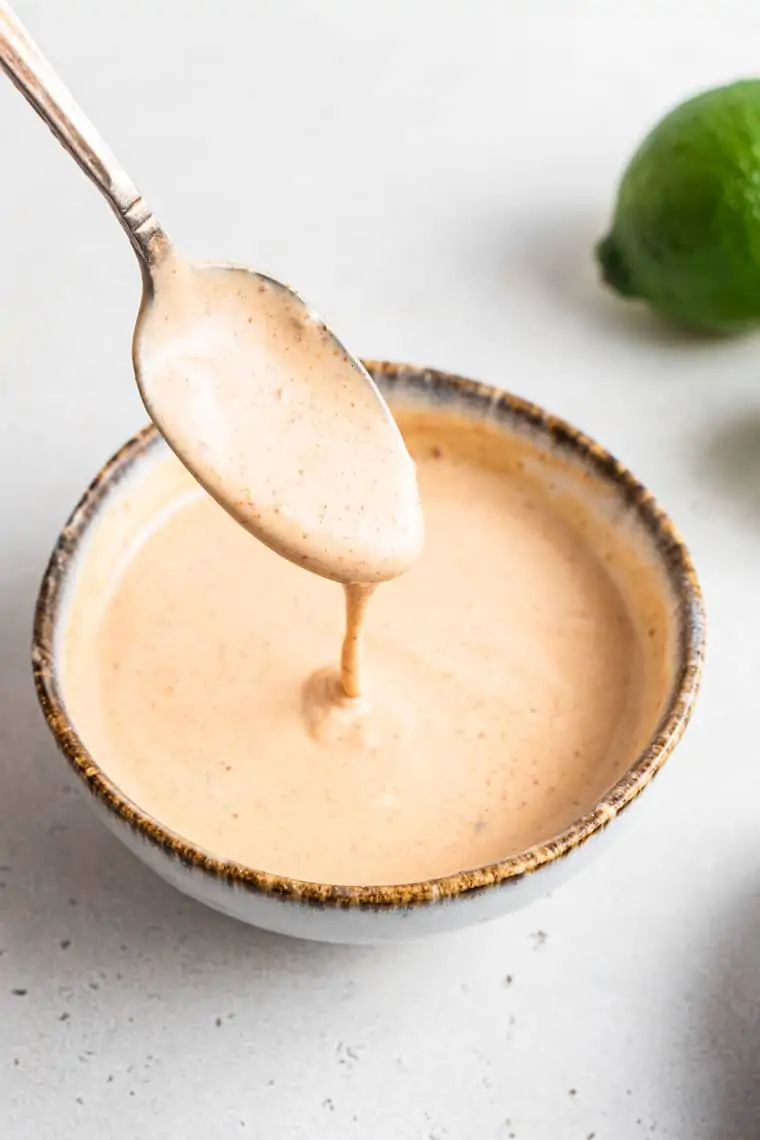 white bowl of tahini dressing with a spoon