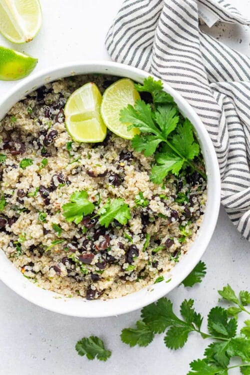 overhead of a white bowl of quinoa salad with beans, lime and cilantro