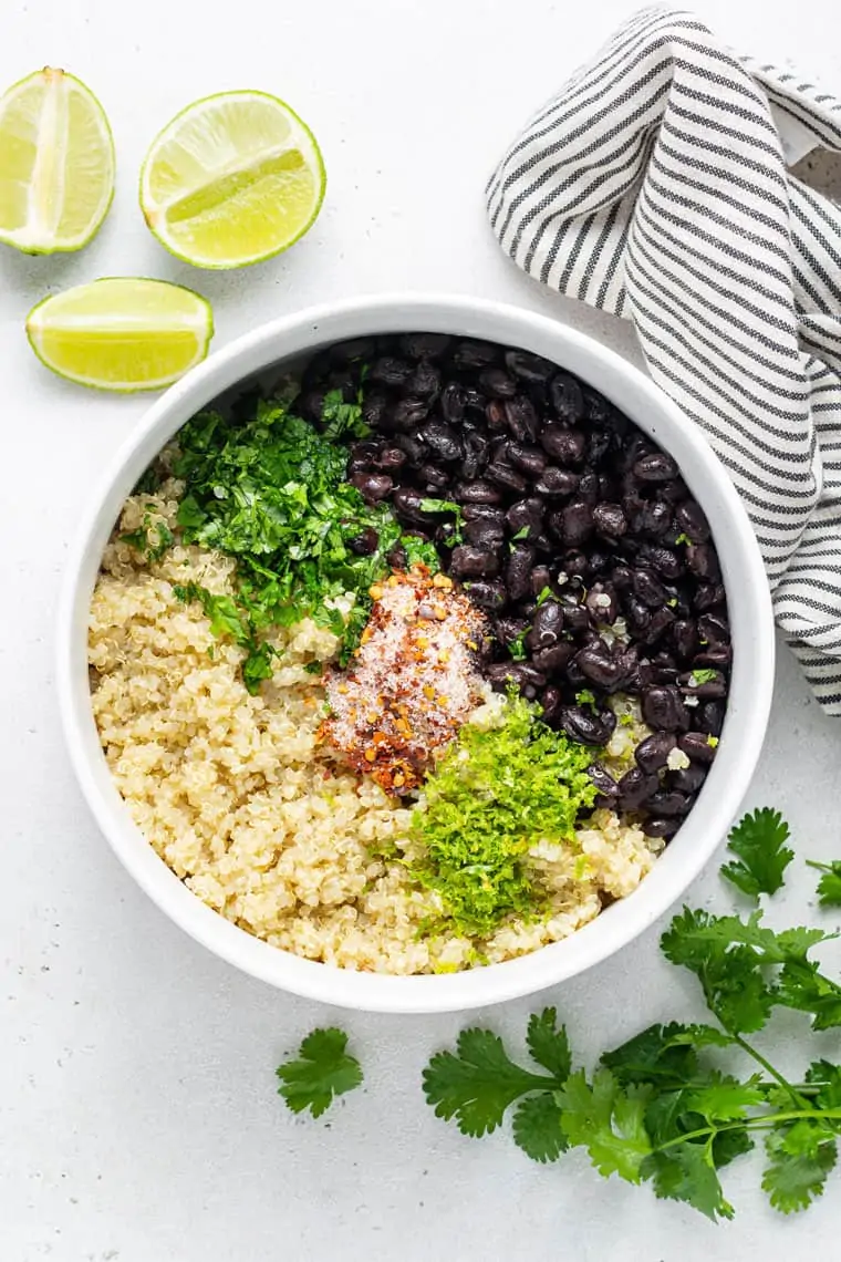 overhead of a white bowl with the ingredients for black bean, quinoa and cilantro salad