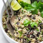 white bowl of cilantro and bean salad with fresh cilantro and limes