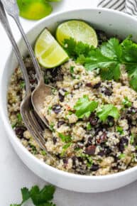 white bowl of cilantro and bean salad with fresh cilantro and limes