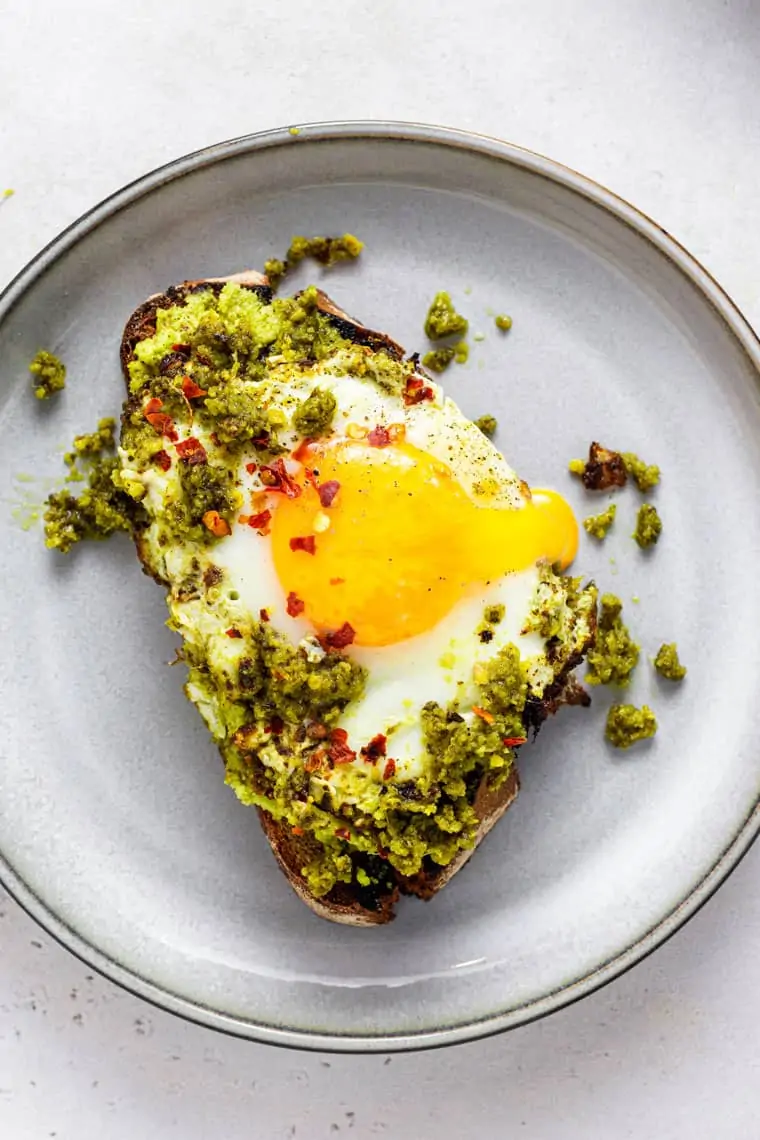plate with a slice of toast and pesto egg on top
