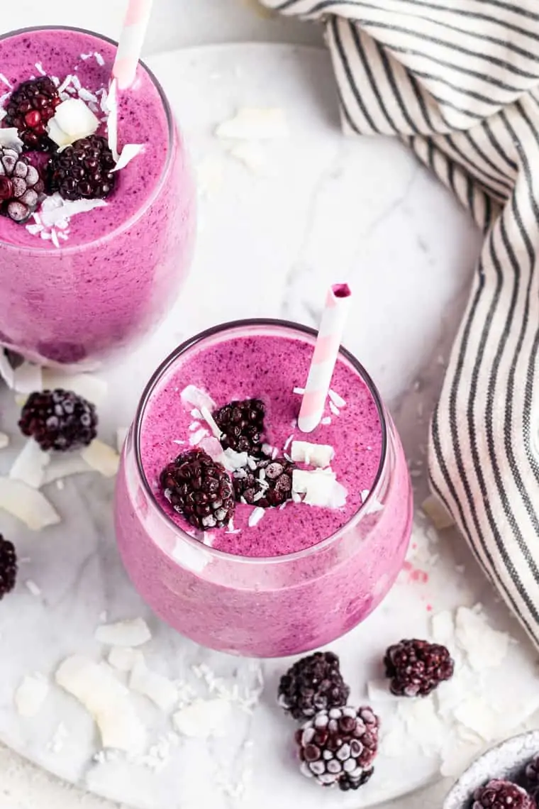 Blackberry smoothies in two glasses with frozen berries