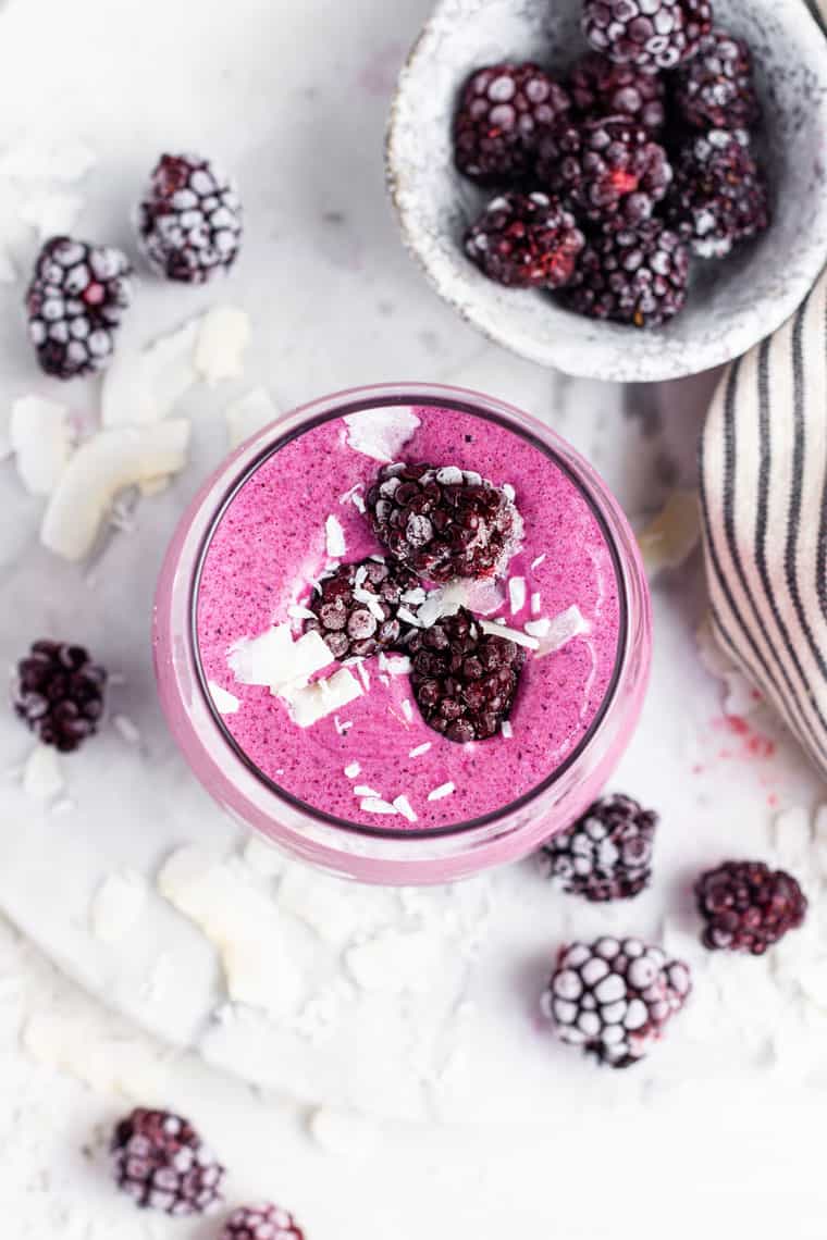 healthy blackberry smoothie on a marble counter with frozen berries
