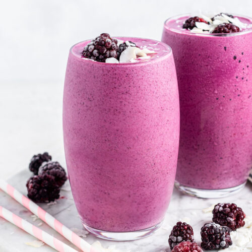 two glasses of pink smoothie with blackberries and pink straws