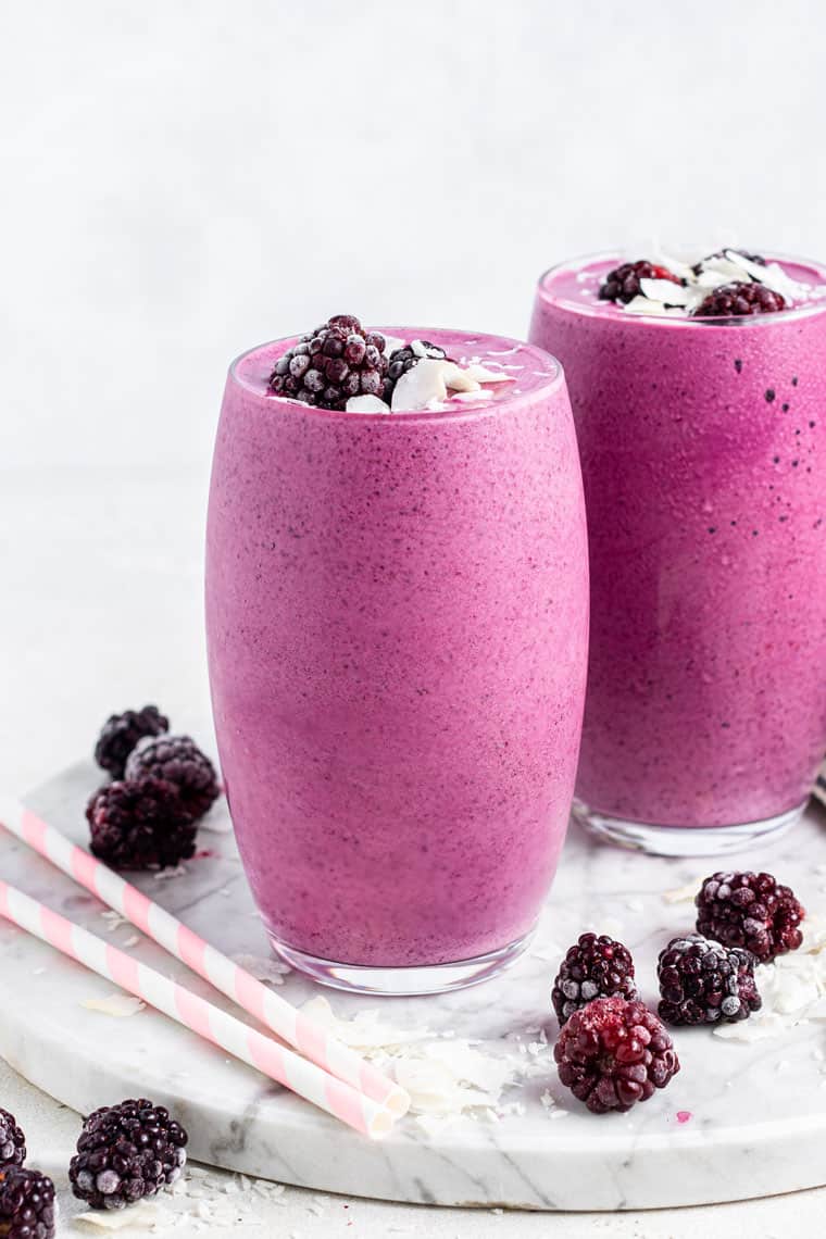 two glasses of pink smoothie with blackberries and pink straws
