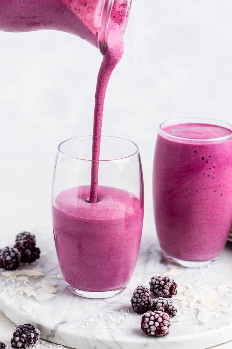 pouring blackberry smoothies into glasses