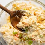 spoon holding a scoop of potaot salad over a bowl of potato salad