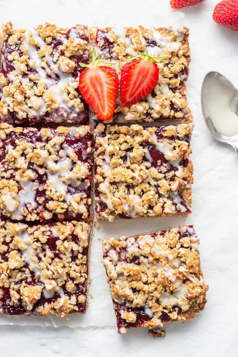 slices of strawberry oatmeal bars with white glaze and fresh berries