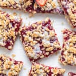 overhead of strawberry oatmeal bars with white glaze and fresh berries