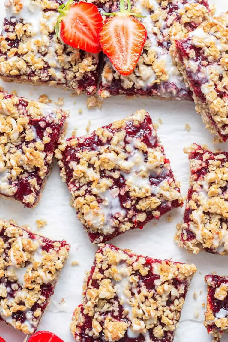 overhead of strawberry oatmeal bars with white glaze and fresh berries