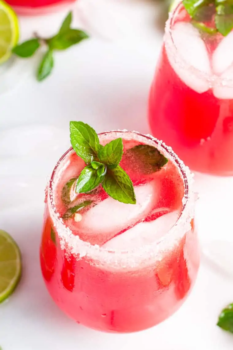 two glasses with fresh watermelon margarita on ice with mint