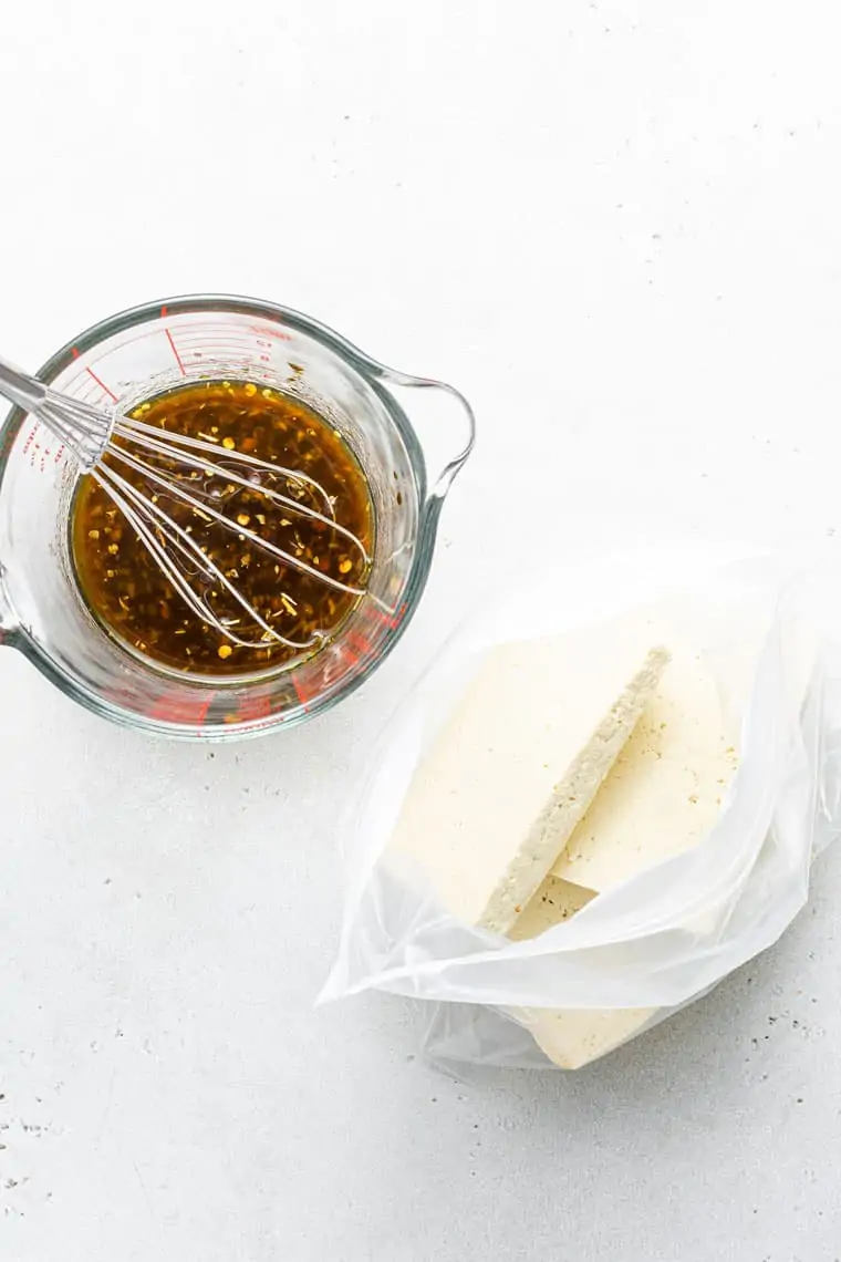 measuring cup with balsamic and pepper marinade with a bag of tofu pieces