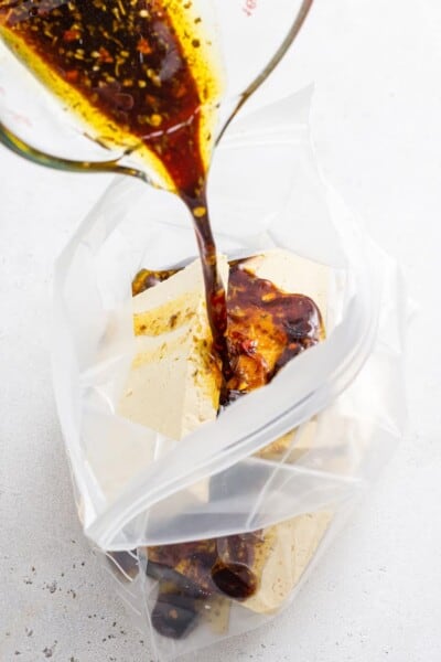 pouring marinade into a bag of tofu pieces