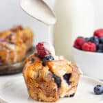 pouring glaze over a berry french toast cup on a plate