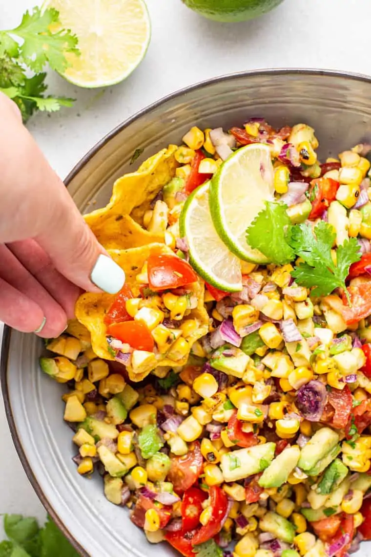 taking a chip of grilled corn avocado salsa