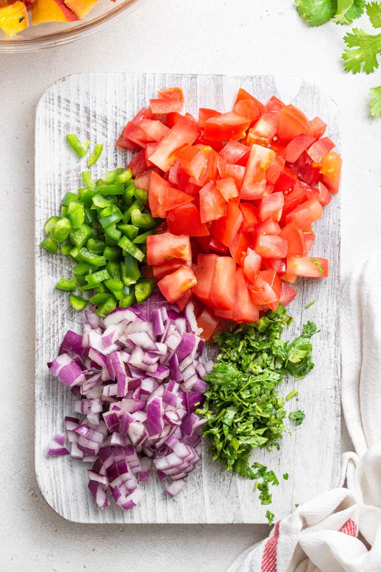 chopped tomato, jalapeno, red onion and cilantro on a cutting board