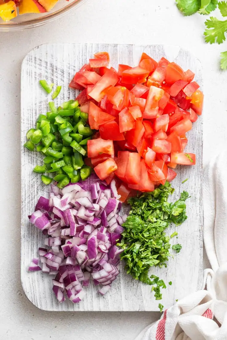 chopped tomato, jalapeno, red onion and cilantro on a cutting board