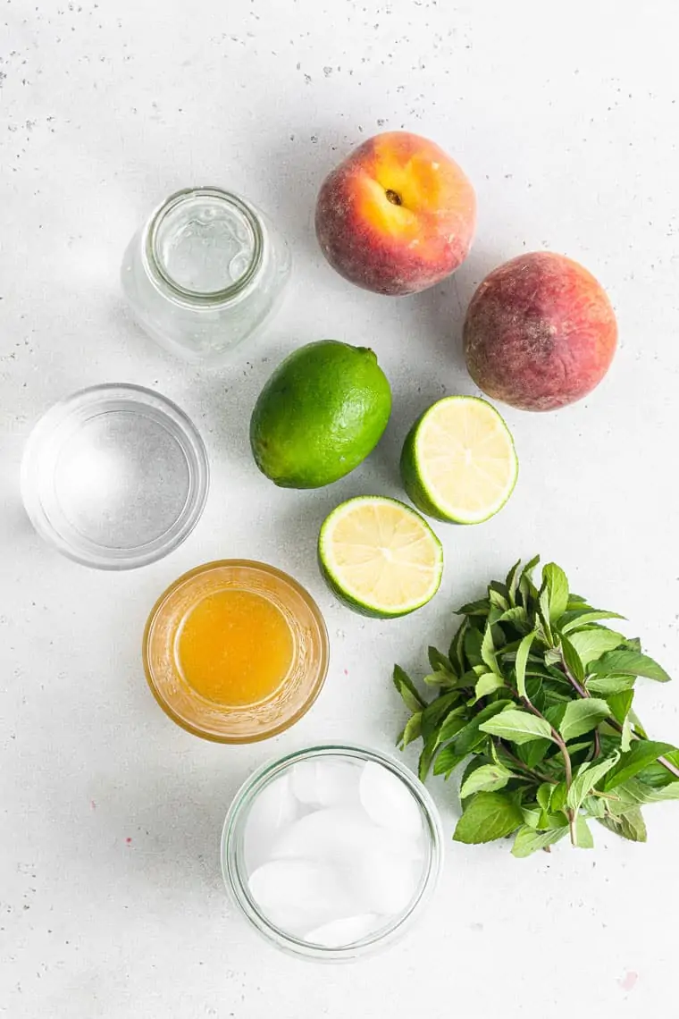 peaches, limes, mint, juice, ice and water on a counter