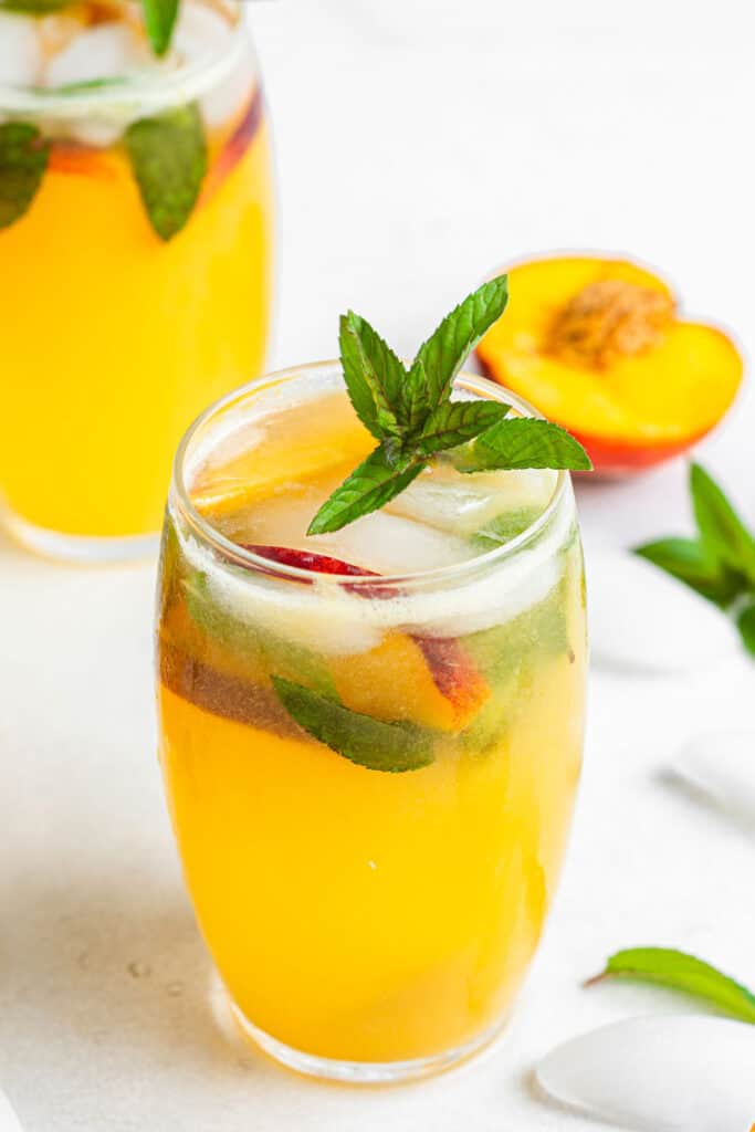 This peach mojito recipe is made with peach purée, white rum, lime, and fresh mint, sweetened with honey for a light, fizzy summer cocktail. A peach mojito garnished with fresh mint and peach wedges.