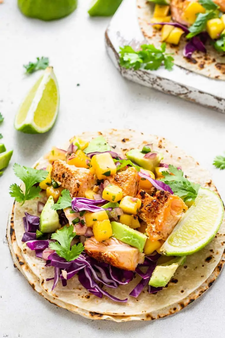 open tortilla with salmon and diced mango and fresh lime slces