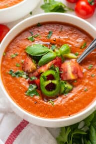 close up on tomato gazpacho ina white bowl with fresh herbs