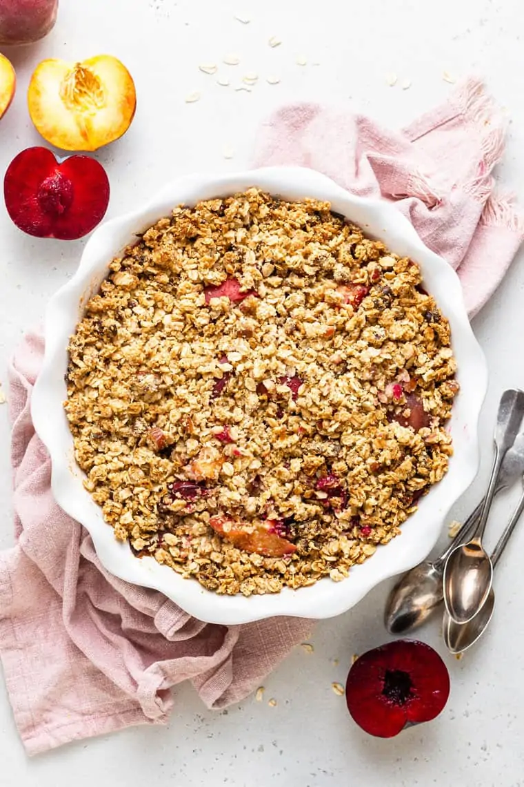 overhead of quiona crumble with stone fruit in a white baking dish