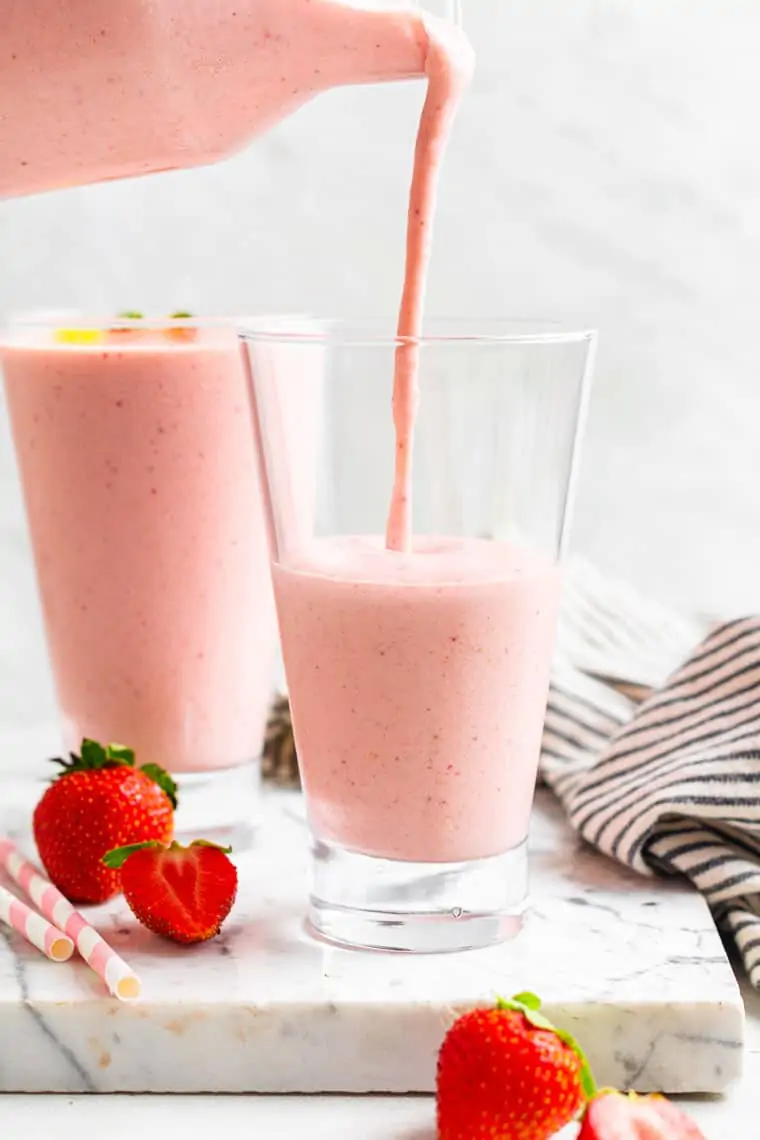 pouring a pink smoothie in to a glass