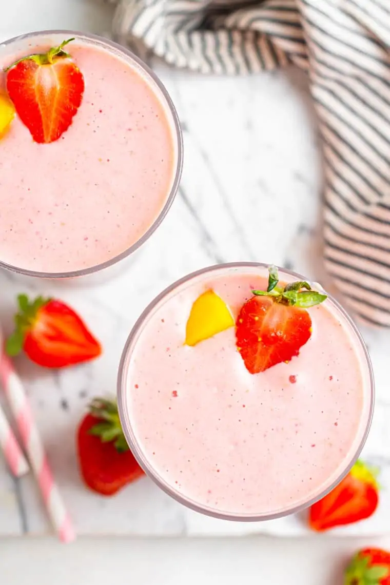 overhead of two glasses of pink smoothies with strawberries