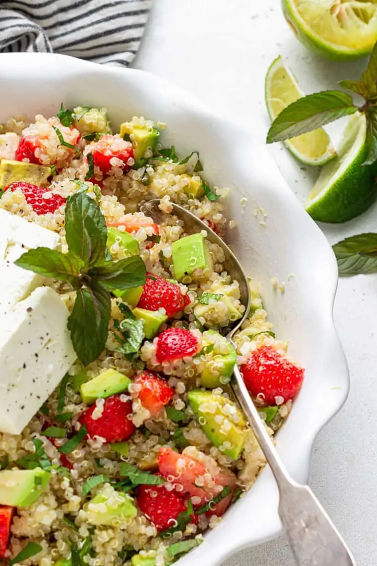bowl of quinoa salad with fresh fruit, avocado, mint and cheese