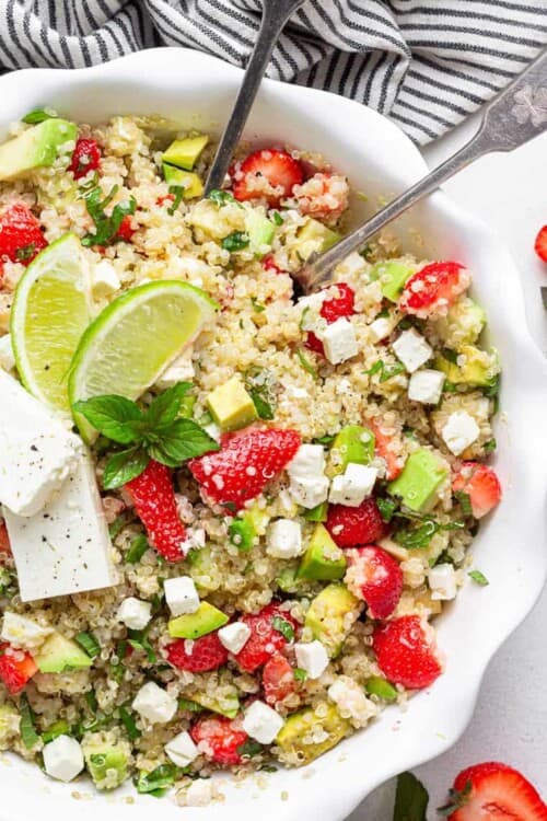 close up on a bowl of strawberry quinoa salad with avocado, cheese and lime