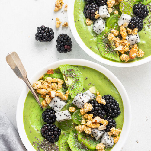 two bowls of green smoothie with fresh fruit