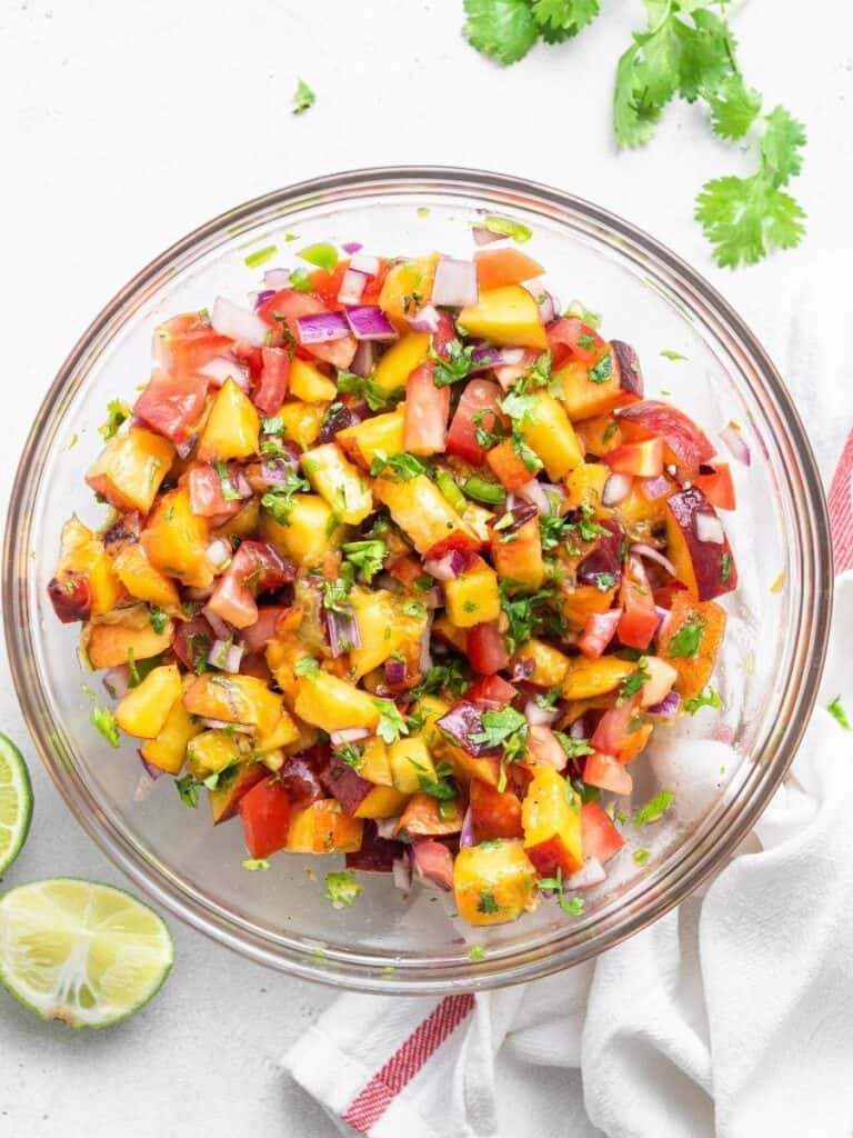 This refreshing Peach Salsa recipe is a sweet, savory and spicy homemade condiment you’ll love with fish, chips and more. Easy and delicious! Overhead view of fresh peach salsa in bowl