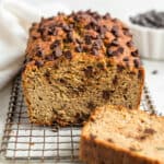 whole loaf of chocolate chip zucchini bread with a slice removed on a wire rack