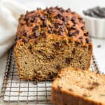 whole loaf of chocolate chip zucchini bread with a slice removed on a wire rack