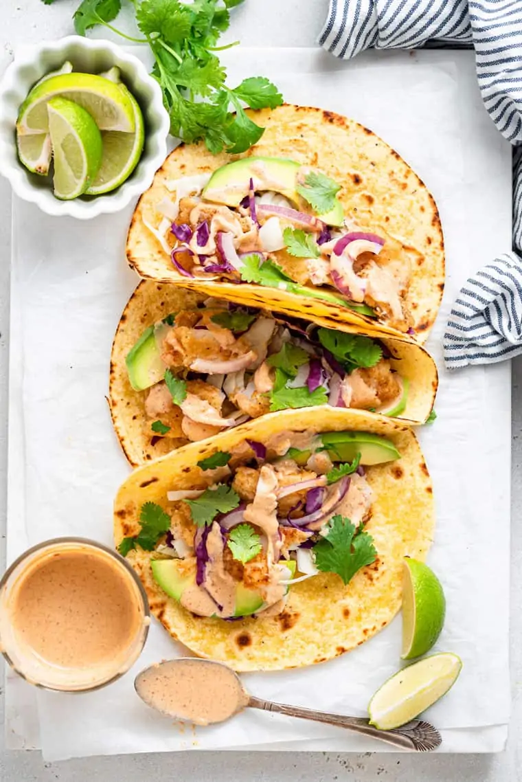 three folded crispy fish tacos in tortillas