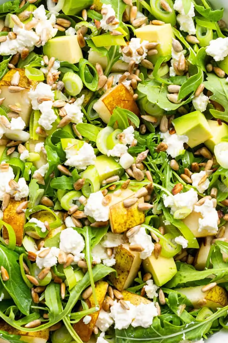 close up on arugula and pear salad with cheese and avocado