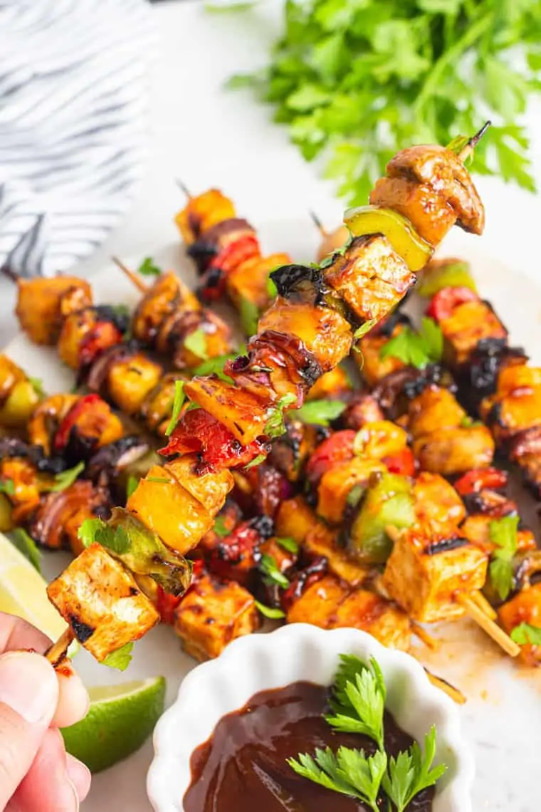 hand holding kebab with tofu and peppers with mushrooms