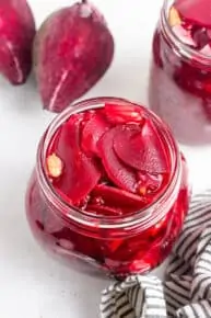 jar of sliced pickled beets with peppercorns