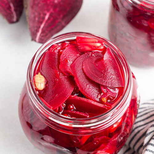 jar of sliced pickled beets with peppercorns