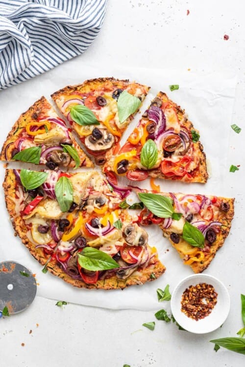 overhead of zucchini pizza crust with colorful veggies