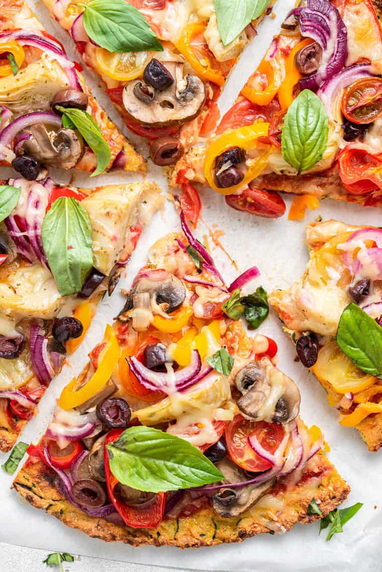 overhead of slices of zucchini pizza with onions, peppers and tomatoes