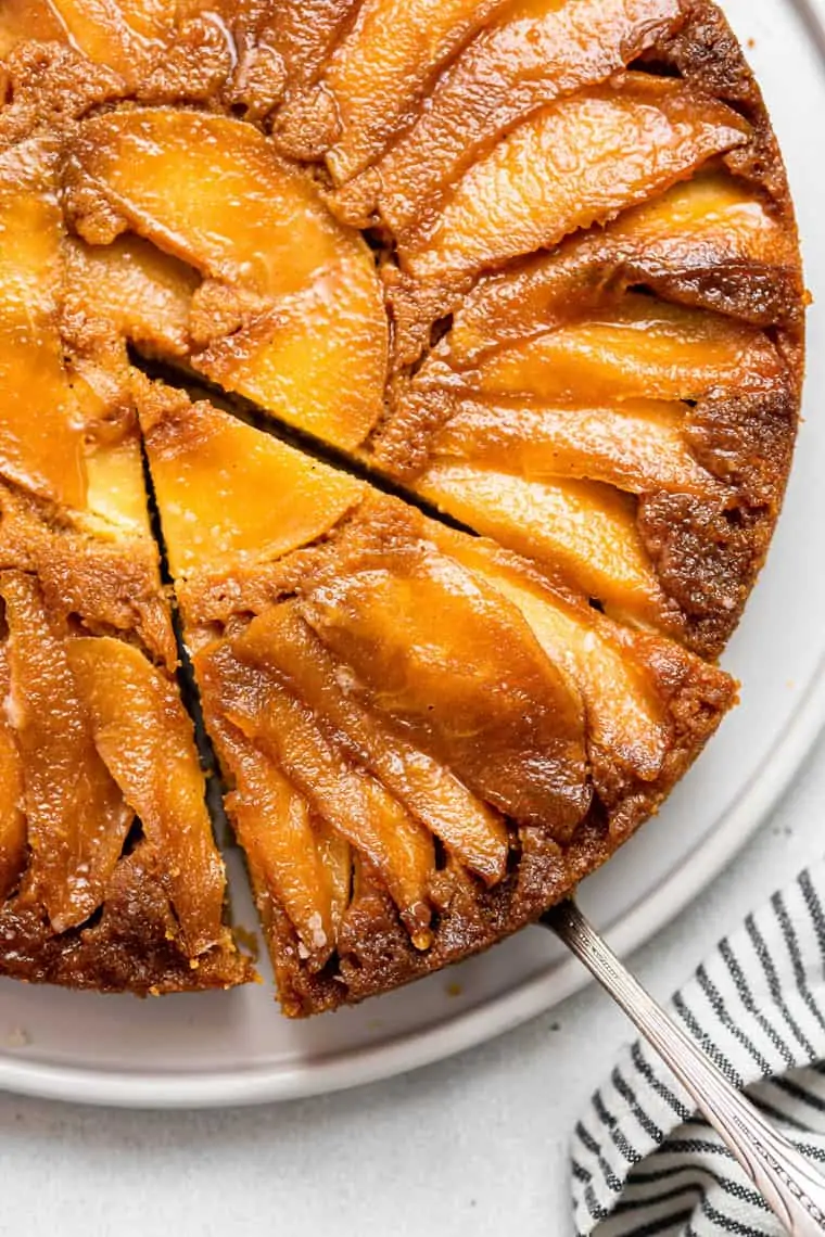 This apple upside-down cake is a show-stopping fall dessert with perfectly layered caramelized apple slices on a tender cinnamon-spiced cake. slcie of upside down apple cake on a pan